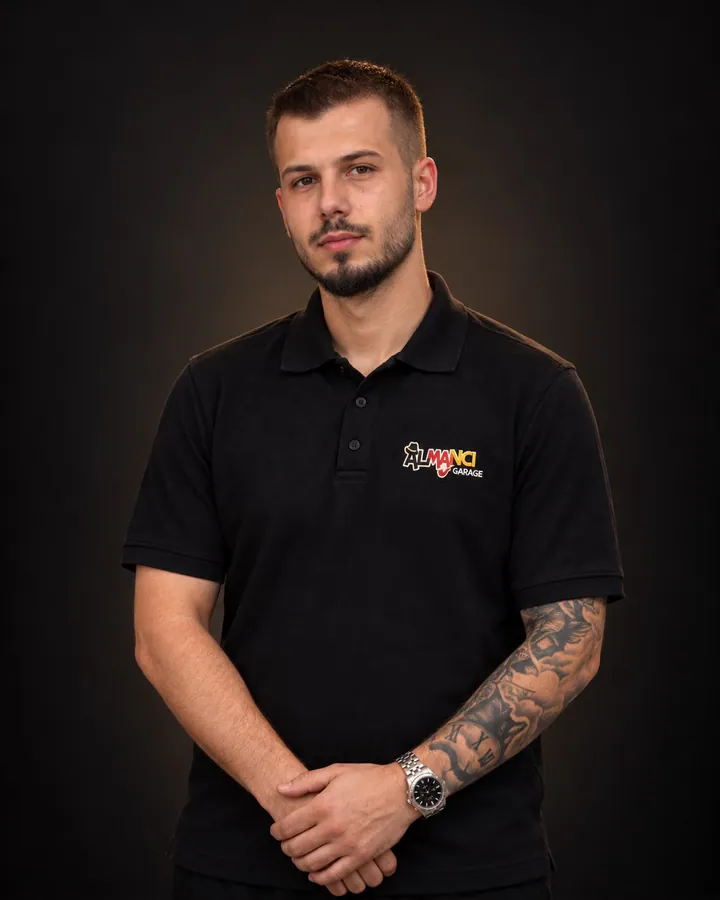 Almancı Garage logolu siyah polo tişörtüyle sakallı ekip üyesi