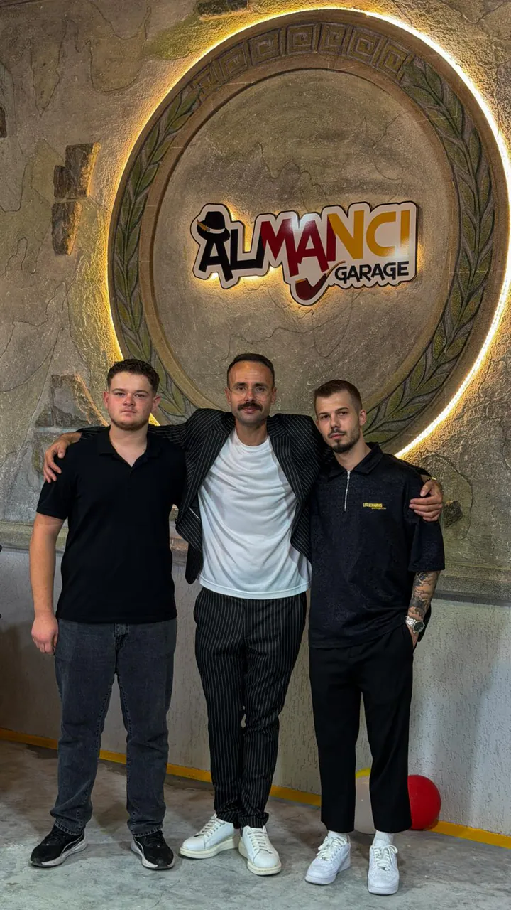 Almancı Garage ekibi, atölyenin logolu duvarının önünde