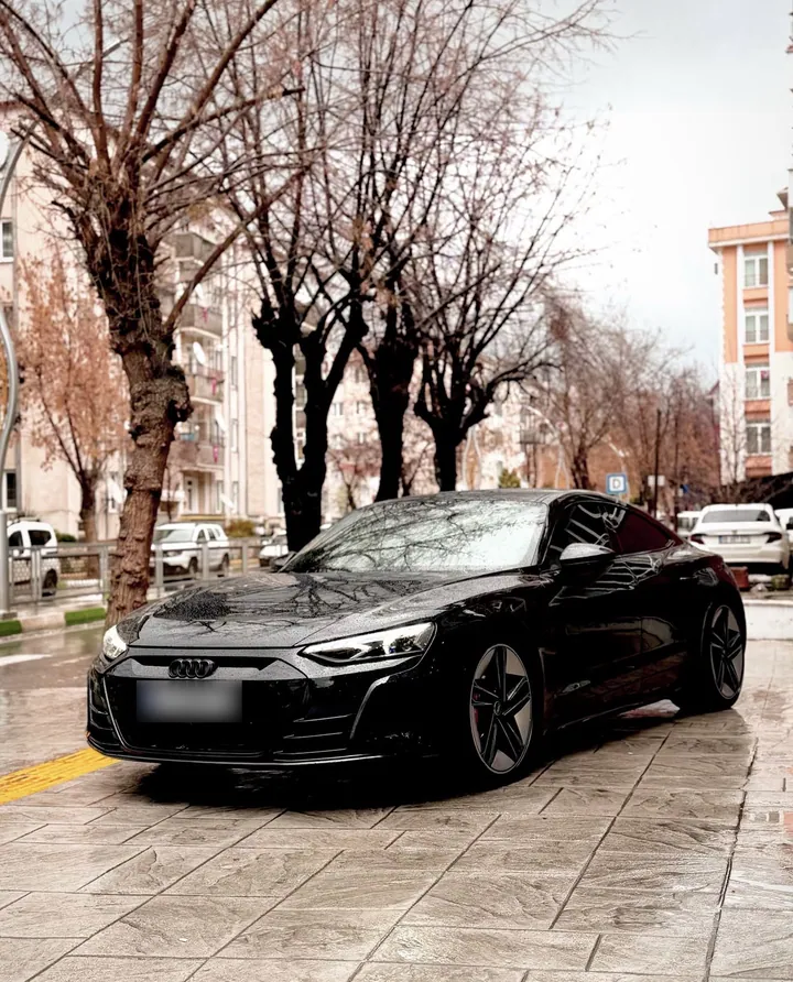 Yağmur sonrası ıslak zeminde siyah Audi e-tron GT, ön çapraz